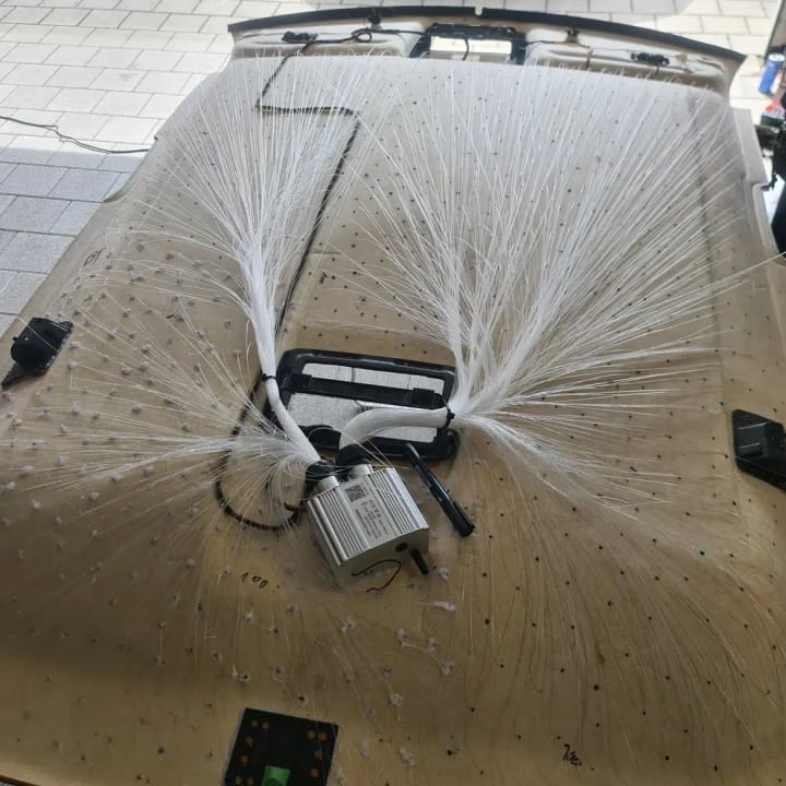 Ausgebauter Dachhimmel eines Golf 8 GTI mit hunderten eingesetzten Glasfasern, die zu einem Bündel an einem Aluminiummodul zusammenlaufen.
